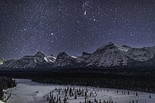 Sous une nuit brillamment étoilée un paysage de neige avec une belle vallée et de grandes montagnes.