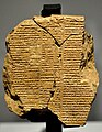 Tablette d'argile montée sur un pied et recouverte de caractères cunéiformes. Elle est traversée de fissures qui la divisent en trois parties.