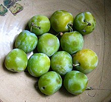 Fruits ronds, verts ou tirant sur le jaune, dans un plat gris en céramique