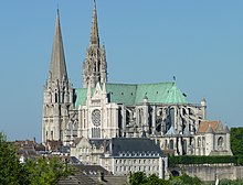 Photographie d'une cathédrale aux toits de couleur verte avec deux clochers de style différent