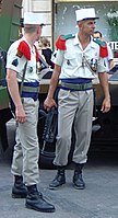 Soldats de la Légion étrangère en uniforme de parade. Épaulettes rouges à parement vert, ceinture bleue et képi blanc distinctif.