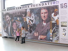 Mur de mosaïque représentant plusieurs images de Mario Lemieux surmontées des mots The Mario Lemieux fondation.