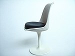 Miniature de la chaise Tulipe sur un fond blanc. Celle-ci se compose d'un pied corolle blanc, d'une coque blanche incurvée. L'assise est noire.