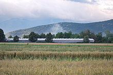 Photographie de champs de céréales et d'une ferme industrielle dans le Polog