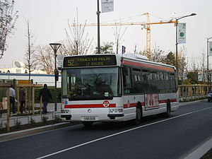Photographie d'un bus numéroté 52, roulant dans une rue entourée de travaux en direction de Vaulx-en-Velin.
