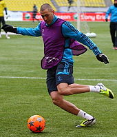 Photo de Karim Benzema sur un terrain de football avec le maillot d'entrainement du Real Madrid, la jambe gauche en extension s’apprêtant à frapper dans le ballon.
