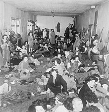 photographie en noir et blanc montrant un groupe de femmes entassées dans un baraquement
