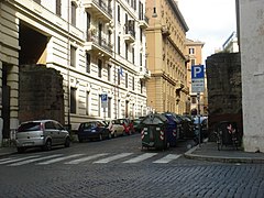 Photographie en couleurs d'une rue passant par la brèche d'une muraille