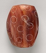 Perle en cornaline à décor blanchi mise au jour à Nippur en Mésopotamie. Musée du Louvre.