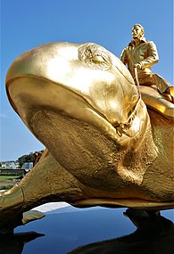 Sculpture d'un homme doré chevauchant une tortue géante et également dorée