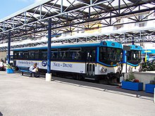 Vue de deux bus en gare routière sous une structure métallique avec le quai en premier plan.