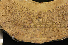 Détail d'une inscription royale, sur des cases ordonnées en arc-de-cercle, à la graphie élégante illustrant un stade intermédiaire de la « cunéiformisation » de l'écriture des inscriptions commémoratives, encore incomplète ici