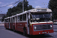 Photographie couleur d'un bus articulé rouge et jaune dans les années 1960.