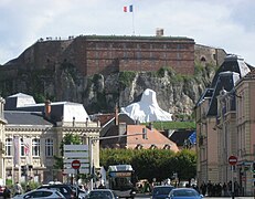 photographie la statue du Lion de Belfort bâchée avant son inauguration avec au premier plan la Vieille Ville et à l'arrière-plan la citadelle et sa caserne.