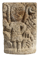 Chapiteau simple en granit sculpté sur une face d'un personnage debout.