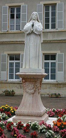 Photo d'une statue de Sainte Bernadette à Nevers, la représentant en sœur, un chapelet à la main