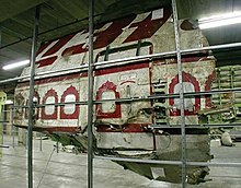 Une portion de fuselage maintenue par une structure métallique, dans un hangar.
