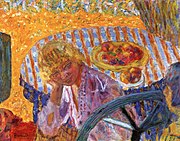 Tableau très coloré représentant devant une table garnie de fruits une jeune femme blonde assise en buste, penchée et souriante, avec en bas à droite le visage coupé d'une autre, brune.