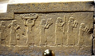 Bas-relief du podium du trône assyrien du palais du Fort Salmanazar de Nimroud, face sud : le roi Salmanazar III reçoit le tribut de Chaldéens, comprenant de l'étain, du bois précieux et de l'ivoire. Musée national d'Irak.