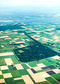 Photographie aérienne des champs et des éoliennes avec un alignement des fermes caractéristique.