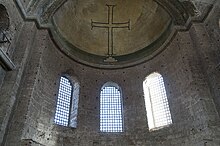 Photographie d'une croix peinte sur le mur intérieur d'une église.
