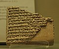 Photographie d'un fragment de tablette intensément gravée d'écriture cunéiforme.