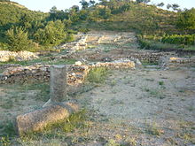 Photographie en couleur de ruines, des fondations de maison, en bord de colline